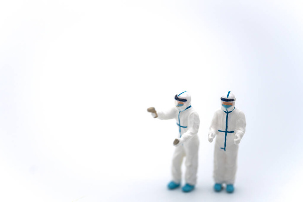 Cuidados de saúde e Pandemia Consept. Dois médicos figura em miniatura pessoas vestindo equipamento de proteção individual, (PPE) roupa com infravermelho Thermo varredura no fundo branco. - Foto, Imagem
