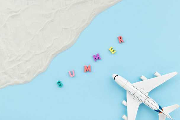 Composición creativa con un avión de juguete, arena e inscripción de verano - Foto, imagen