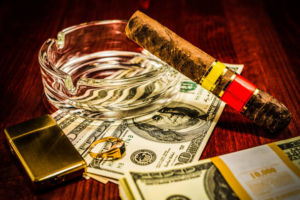 Cuban cigar with glass ashtray on a several dollar bills and als - Foto, imagen