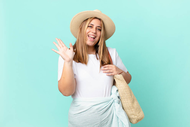 curvy pretty blonde woman smiling happily, waving hand, welcoming and greeting you - Фото, изображение