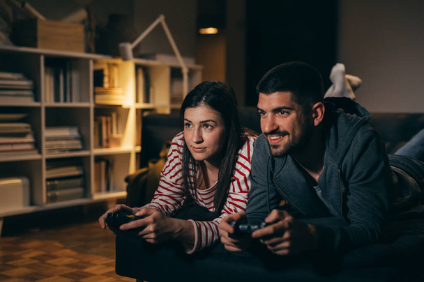couple enjoying evening at home playing video games - Foto, imagen