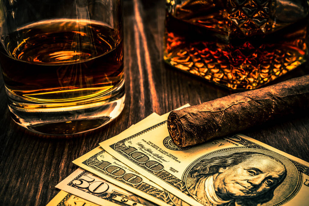 Decanter van whisky en een glas met Cubaanse sigaar en geld op een  - Foto, afbeelding