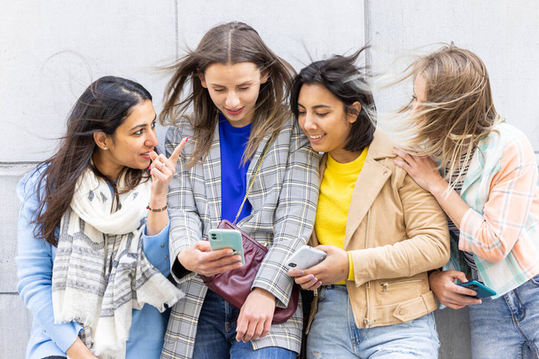 Többnemzetiségű csoport gyönyörű fiatal női barátok álló fal segítségével mobil okostelefonok - Fotó, kép