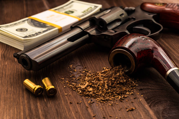 Money and a gun with a pipe on a wooden table - Fotoğraf, Görsel