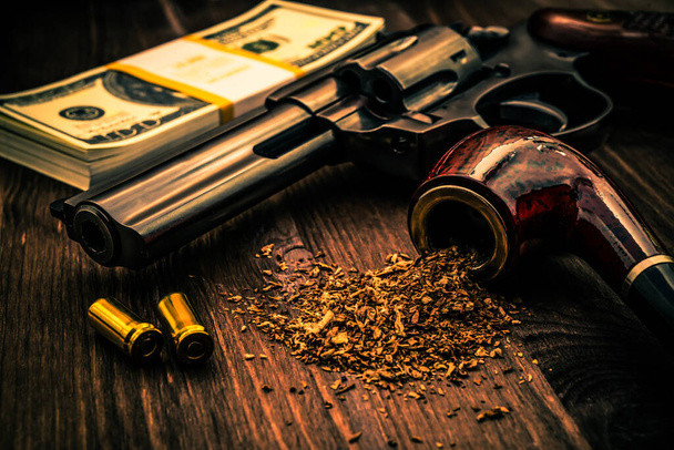 Money and a gun with a pipe on a wooden table - Foto, immagini