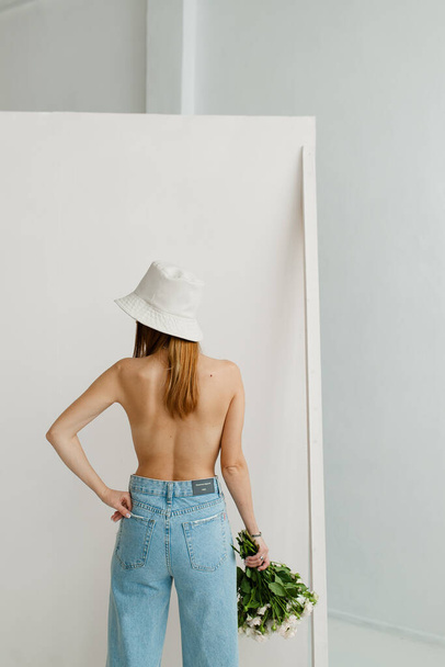 studio photography girl with a bare back on a background of paper backdrops young girl in blue jeans - Foto, afbeelding
