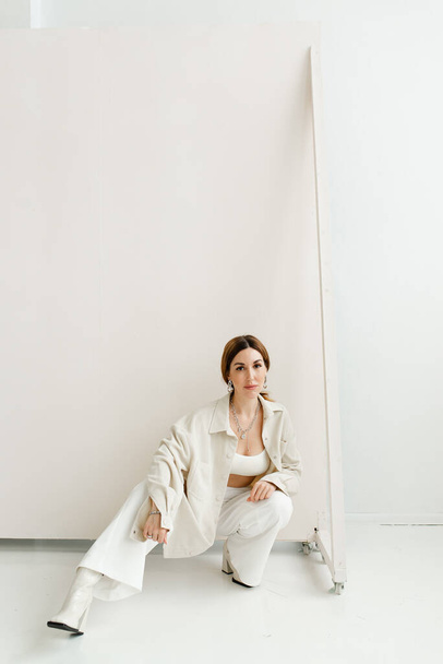 gyönyörű spanyol modell fehér ruhában egy fotózáshoz a stúdióban - Fotó, kép