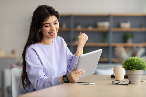 Woman using tablet celebrating success shaking fists - Photo, Image