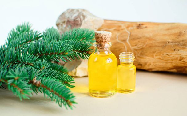 Lucfenyő illóolaj egy palackban, friss lucfenyő gallyak a háttérben. Aromaterápia, spa, homeopátia - Fotó, kép
