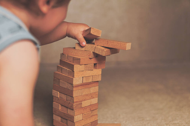 The child's hands pushed the brick and destroyed the tower. Janga wooden box. An imbalance. destruction of blocks. Mistake. Entertainment activities. A game of physical and mental skill. - Fotoğraf, Görsel