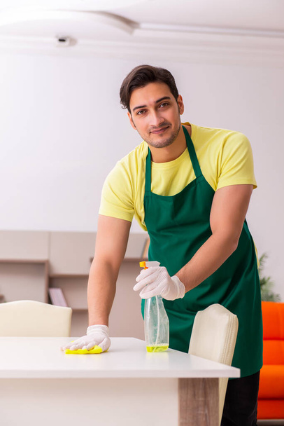 Joven contratista masculino limpiando la casa en interiores - Foto, Imagen