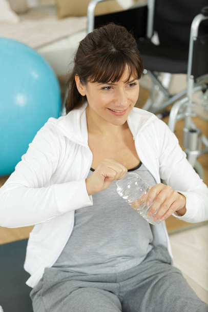 woman drinking water in locker room after fitness training - Foto, Imagem
