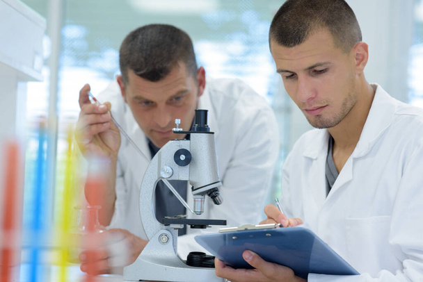 male scientists with clipboard and microscope in lab - Foto, Imagen