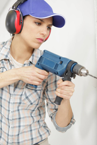 closeup of a young woman drilling wall - Fotó, kép