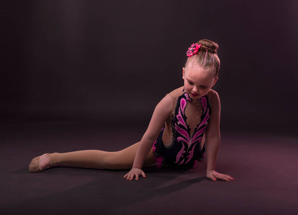 Funny cute little girl trying to do splits in gymnast costume, stretching - Foto, Imagem