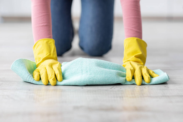 Tanımlanamayan kadın yerleri temizliyor, lastik eldiven takıyor. - Fotoğraf, Görsel