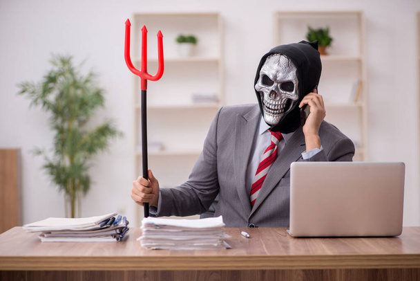 Ördög üzletember alkalmazott ül a munkahelyen - Fotó, kép
