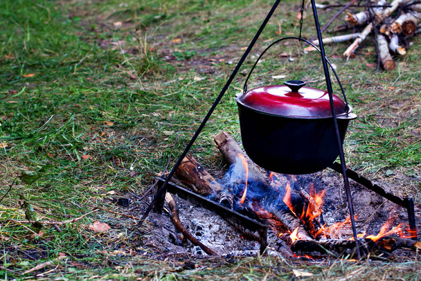 Un pot au-dessus du feu. Vacances d'été, randonnée, tourisme. Bouilloire touristique fumée sur le feu de camp.   - Photo, image