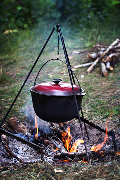 A pot over the fire. Summer vacation, hike, tourism.  Smoked tourist kettle over campfire.   - Φωτογραφία, εικόνα