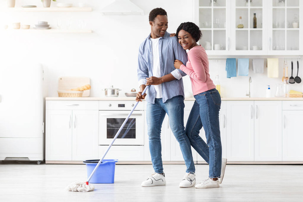 pozytywny czarny para sprzątanie kuchnia razem i przytulanie - Zdjęcie, obraz