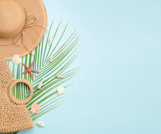 chapeau de soleil, sac de plage, feuilles de palmier et coquillages sur fond bleu clair. fond d'été - Photo, image