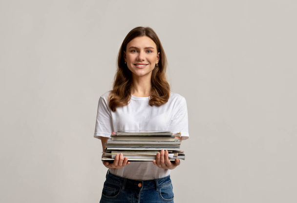 Waste Sorting. Portrait Of Beautiful Young Woman Holding Stack Of Old Magazines - 写真・画像