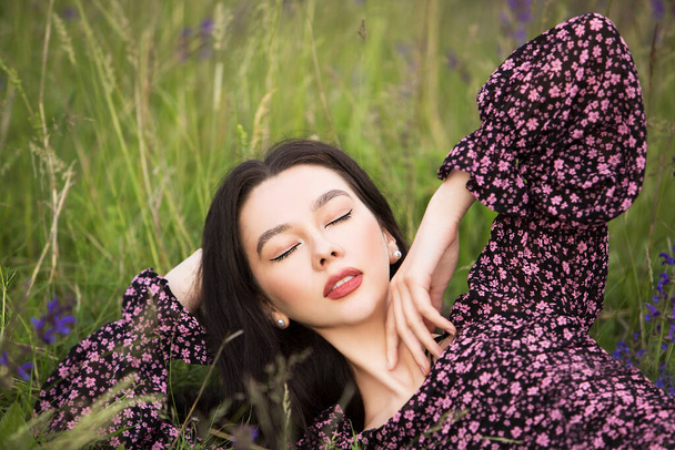 Młoda piękna dziewczyna leżąca wśród dzikich kwiatów w letni dzień. - Zdjęcie, obraz