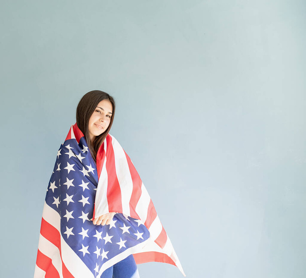 belle jeune femme avec drapeau américain sur fond bleu - Photo, image
