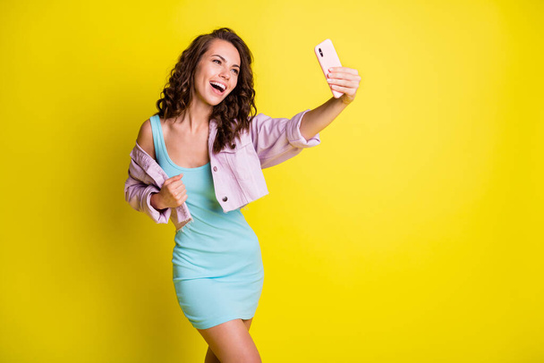 Portret van aantrekkelijke vrolijke golvende harige meisje nemen maken selfie plezier geïsoleerd over helder gele kleur achtergrond - Foto, afbeelding