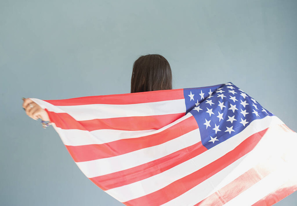 beautiful young woman with american flag on blue background - Fotoğraf, Görsel