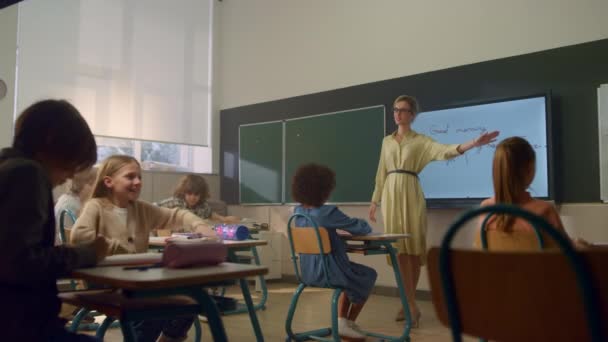 Schüler lernen in der Grundschule. Lehrerin steht an der Tafel - Filmmaterial, Video