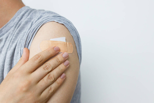 Coronavirus-Impfkonzept. Klebeverband am Arm des Mannes nach der Impfung. Covid-19-Impfprogramm. Prävention, Behandlung und Schutz vor Coronavirus - Foto, Bild