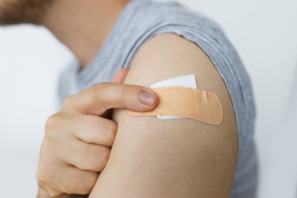 Coronavirus Vaccination concept. Adhesive bandage on man arm after vaccine injection. Covid-19 immunization program. Prevention, treatment and protection from coronavirus - Photo, image