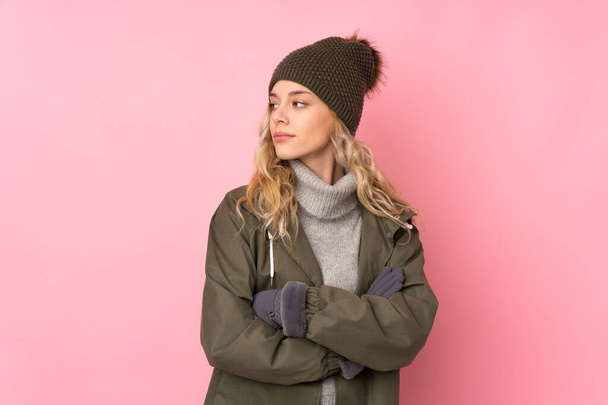 Young girl with winter hat isolated on pink background looking side - Zdjęcie, obraz