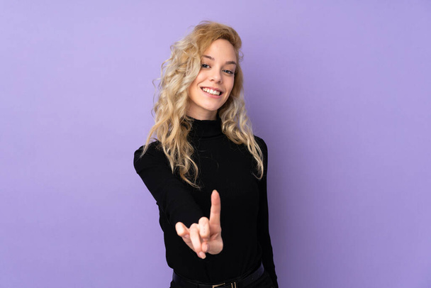 Молода блондинка ізольована на фіолетовому фоні, показуючи і піднімаючи палець
 - Фото, зображення