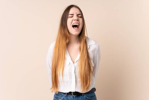 Young caucasian woman isolated on beige background shouting to the front with mouth wide open - Photo, Image