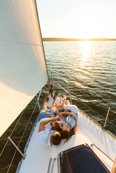 Relaks rodzinny Leżąc na pokładzie jachtu patrząc na zachód słońca na zewnątrz - Zdjęcie, obraz