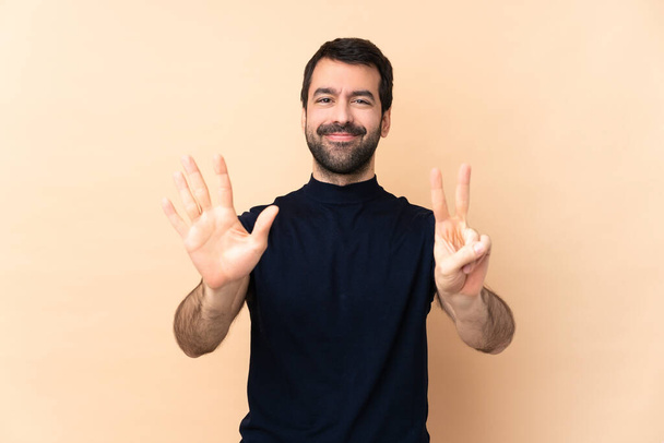 Kaukasischer gutaussehender Mann über isoliertem Hintergrund, der mit Fingern sieben zählt - Foto, Bild
