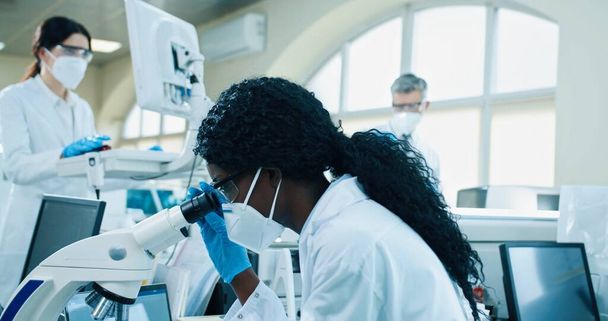 African American scientist working in labs on AIDS cure. Chemical expert looking at analysis through microscope, developing coronavirus medication, examining blood cells. Medicine, close up concept - Φωτογραφία, εικόνα