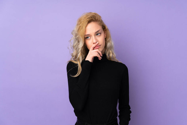 Young blonde woman isolated on purple background having doubts and with confuse face expression - Фото, зображення