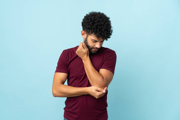 Young Moroccan man isolated on blue background with pain in elbow - Fotó, kép