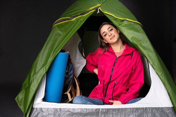 Молодая белая женщина в кемпинге зеленая палатка страдает от боли в спине за то, что сделал усилие - Фото, изображение