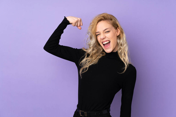 Young blonde woman isolated on purple background doing strong gesture - Fotografie, Obrázek