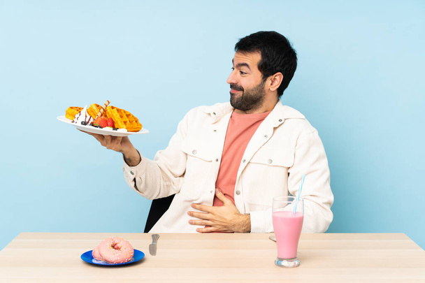 Άνθρωπος στο τραπέζι που τρώει βάφλες και μιλκσέικ. - Φωτογραφία, εικόνα