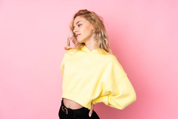 Junge blonde Frau trägt Sweatshirt isoliert auf rosa Hintergrund und leidet unter Rückenschmerzen, weil sie sich bemüht hat - Foto, Bild