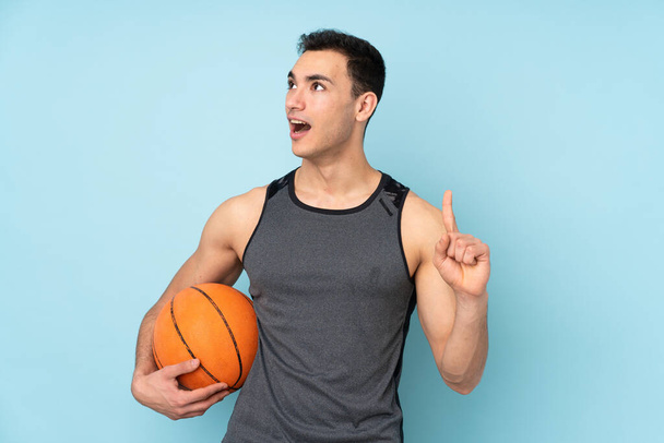 Άνθρωπος σε απομονωμένο μπλε φόντο που παίζει μπάσκετ και έχει μια ιδέα - Φωτογραφία, εικόνα