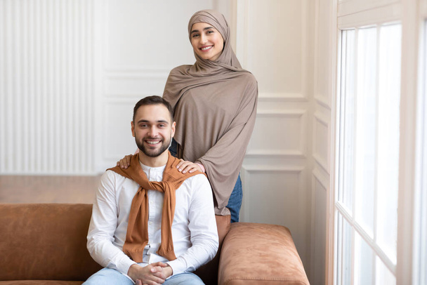 Getrouwd Midden-Oosters paar poseren samen glimlachend naar camera thuis - Foto, afbeelding