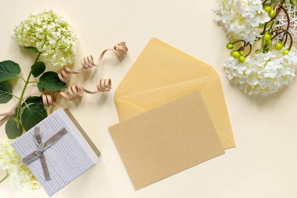 Gift box with bouquet of white hydrangea on beige table. Greeting card for the holiday. Envelope with invitation or congratulation. - Fotografie, Obrázek