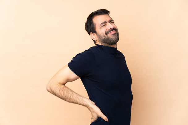 Kaukasischer gutaussehender Mann mit isoliertem Hintergrund, der unter Rückenschmerzen leidet, weil er sich bemüht hat - Foto, Bild