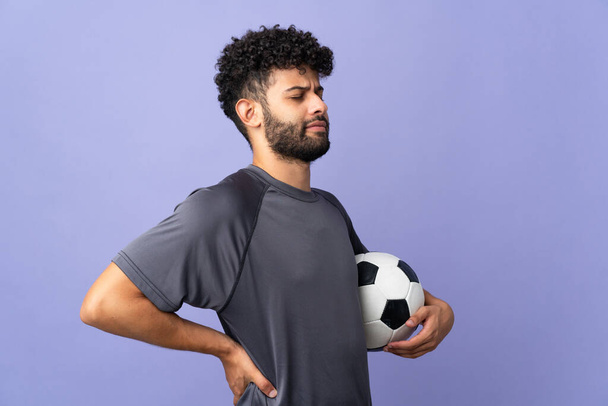 Schöner junger marokkanischer Fußballspieler über isoliert auf violettem Hintergrund, der unter Rückenschmerzen leidet, weil er sich bemüht hat - Foto, Bild